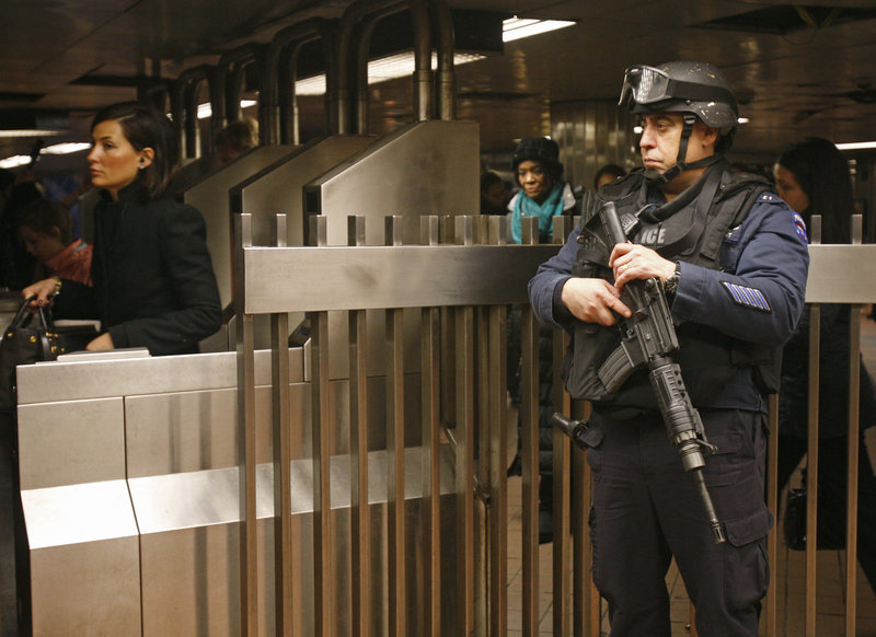 A counterterrorism officer stationed at Grand Central Station in New York keeps his eye on commuters at the subway turnstiles on Monday,