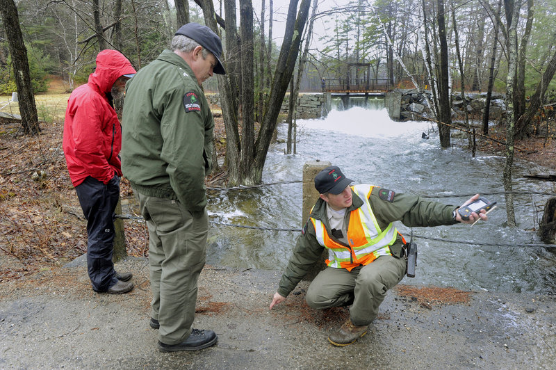 Forest Ranger Matt Bennett, right, explains the flooded road conditions ahead to his supervisor, Gregg Hesslien, while monitoring the outlet dam on Bickford Pond in Porter. A collapsed dam prompted emergency officials to close nearby Colcord Pond Road.