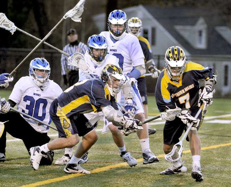 Mark White, right, and Kayle Hamilton of the University of Southern Maine scramble for a loose ball in front of St. Joseph’s goalie Christopher Driscoll, 30, during Wednesday night’s men’s lacrosse game at Deering High. White and Hamilton each had three goals in USM’s 18-5 victory.