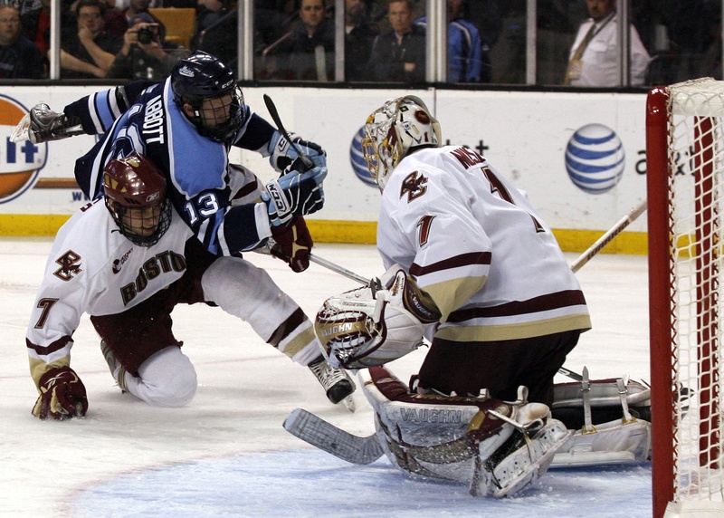 Boston College goalie John Muse stands his ground Saturday night as Spencer Abbott of the University of Maine is upended by Carl Sneep. Boston College won in overtime.