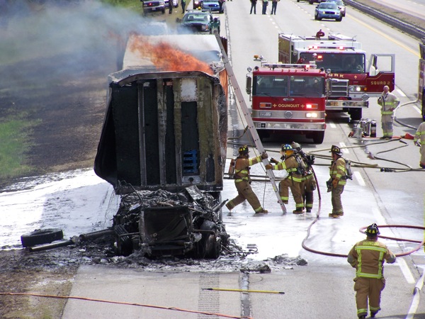 Firefighters work to extinguish the flames that consumed the cab of the tractor-trailer truck.
