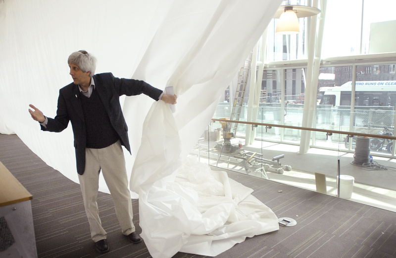 Steve Podgajny, executive director of the Portland Public Library, pulls back a drop cloth to show off the view, and the amount of sunlight, that library users will enjoy after the addition of large windows as part of a remodeling of the library.