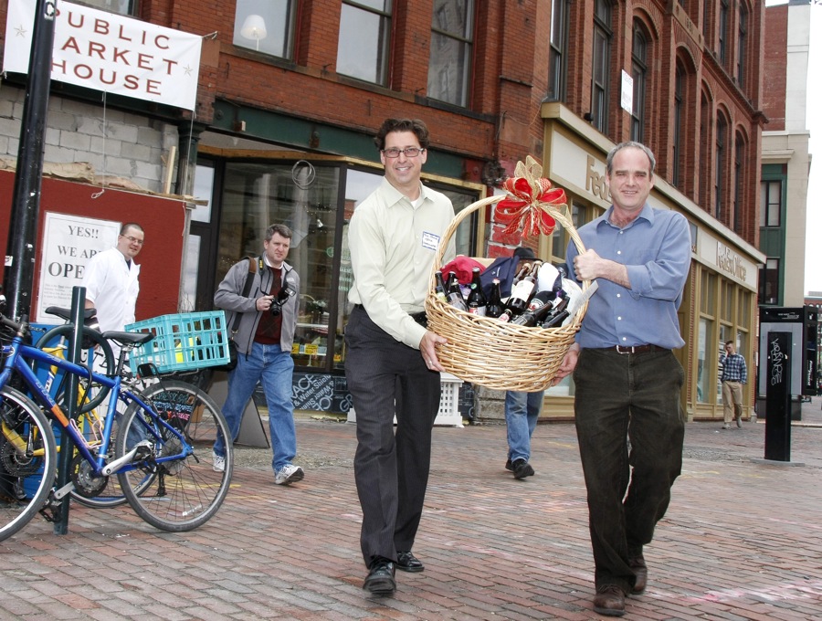 Paul Drinan, left, media coordinator, and store owner Bill Milliken carry a basket of assorted Maine microbrews, along with assorted other Maine products from the Portland Market House, out to a car at Monument Square where it will begin it's journey to President Obama Monday, April 19, 2010. (Jill Brady/Staff Photographer)