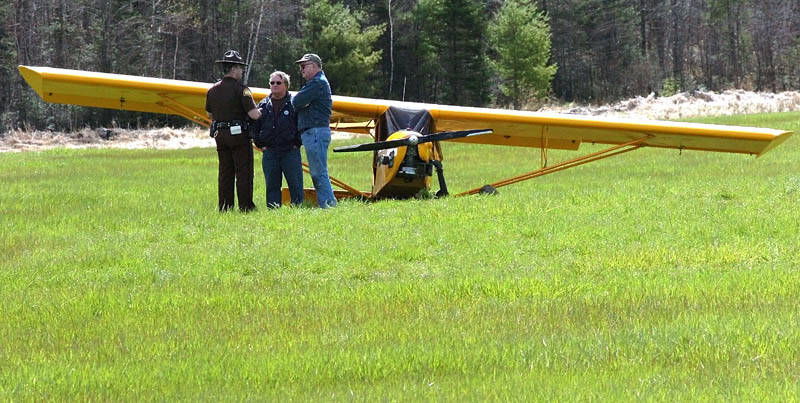 DOWN: Pilot Alton Carter, right, of Industry, speaks with Somerset Deputy Ritchie Putnam beside Carter's airplane, which crashed Tuesday in a wet field off Elm Street in Mercer. At center is Donald Carr, whom Carter called to tell that he had crashed. There were no injuries, and the FAA is investigating the incident.