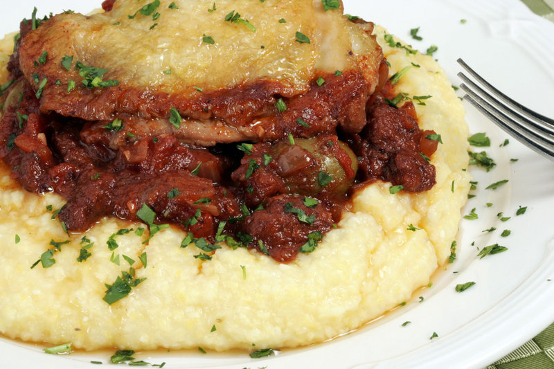 polenta topped with braised chicken and sausage with green olives.