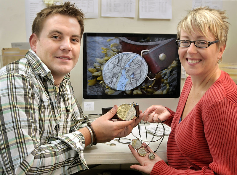 John Guptill and Charlotte Leavitt of Chart Metalworks with some of their jewelry creations fashioned from cutouts of nautical charts.