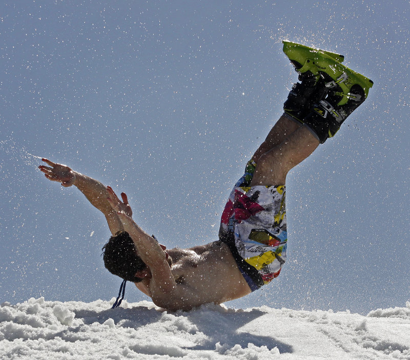 Tony Blout, a senior at Bowdoin College, slides onto the snow after crossing the pond on one ski.
