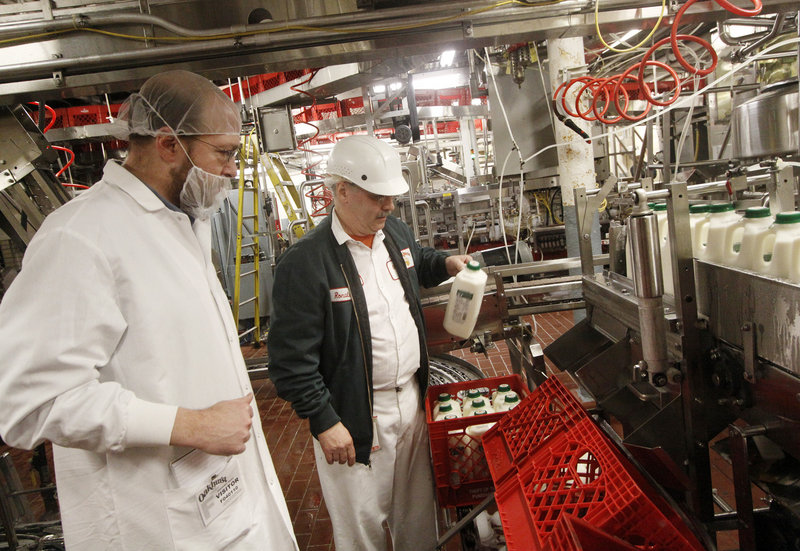 Reporter Ray Routhier, left, works with Ronald Madore Jr. on the bottling line at Oakhurst Dairy in Portland. Madore, who's worked at Oakhurst for 40 years, runs quality checks every 15 minutes.