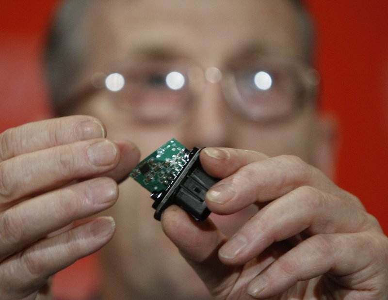 Anthony Anderson, an electrical failure expert, holds an electronic chip from a gas pedal assembly during a news conference March 23. Some groups say electronics could be the cause of sudden acceleration in Toyotas.