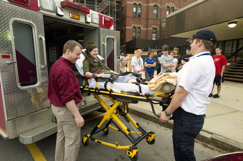 At a recent session focusing on ambulance- and rescue-related careers, Butch Russell (left), clinical director for North East Mobile Health Services, and paramedic Don Bouchard demonstrate the use of their high-tech stretcher to Kelsey Leeman and the other Explorers.
