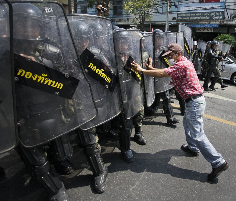 An anti-government demonstrator attempts to hold back an advancing line of Thai soldiers Saturday in Bangkok.