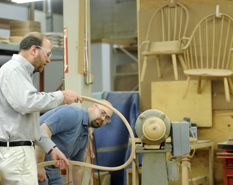 George Colby Jr., right, a cabinetmaker at Thos. Moser Cabinetmakers in Auburn, shows Ray Routhier how to sand the back of a chair.