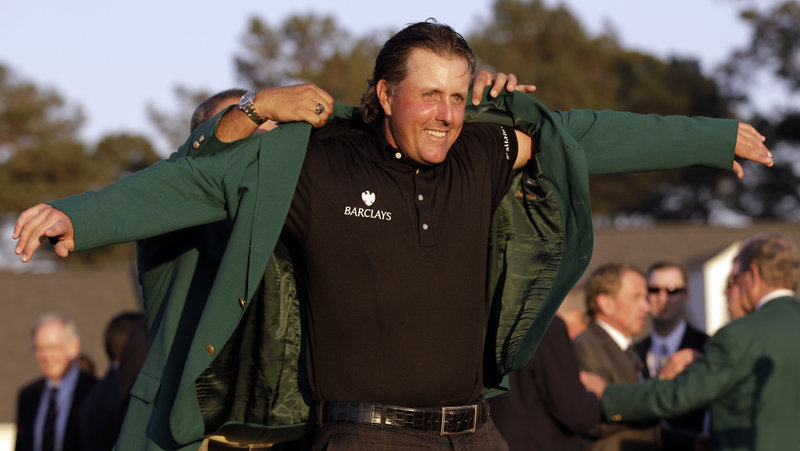 With an assist from former champion Angel Cabrera, Phil Mickelson slips into the traditional winner’s green jacket Sunday after completing a three-shot victory with a final-round 67. It was Mickelson’s third Masters title.
