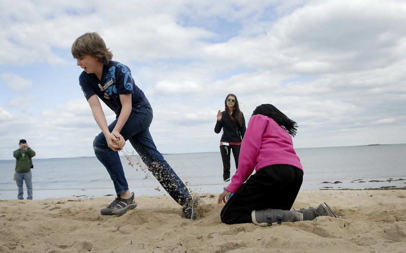 Lucien Cheney takes sand from a bucket as Tshephiso Tselele puts sand back as part of a relay drill that was aimed at showing how the ocean waves shift beach sand, during Lincoln Middle School’s visit to the Ferry Beach Ecology School in Saco on Monday.