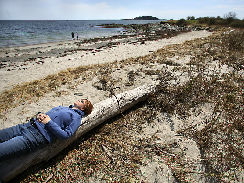 Jennifer Gerow of Portland soaks up the sun during a visit this week to the southern end of Crescent Beach in Cape Elizabeth. The Sprague Corp. owns the state park’s access road, about a quarter of the parking lot and 1,000 feet of ocean frontage.