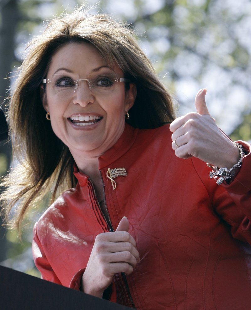 Sarah Palin gestures toward her husband as she addresses a tea party crowd Wednesday in Boston.