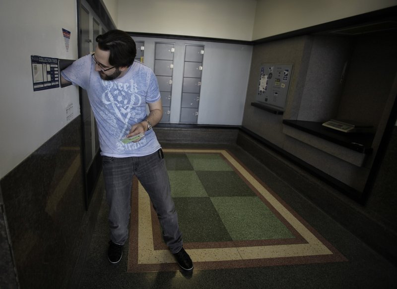 Music producer Alexandre Cardinale sticks his arm inside a mail drop as he mails his tax return forms Wednesday at the Hollywood Station post office in Los Angeles. The average refund this year is about $2,950 – up about $255 over last year.