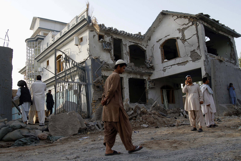 Afghans walk by a house destroyed in a suicide bombing in Kandahar, Afghanistan, on Friday. Fear has gripped the southern city ahead of NATO’s upcoming offensive.
