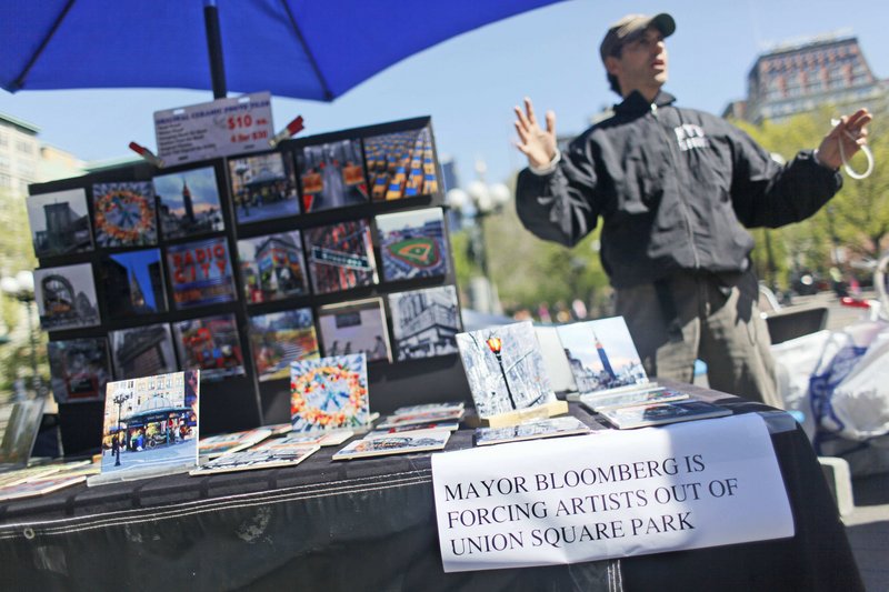 Artist and vendor Joel Kaye expresses his sentiments with a sign at his table in Union Square. Mayor Michael Bloomberg has proposed limiting art vendors’ tables.