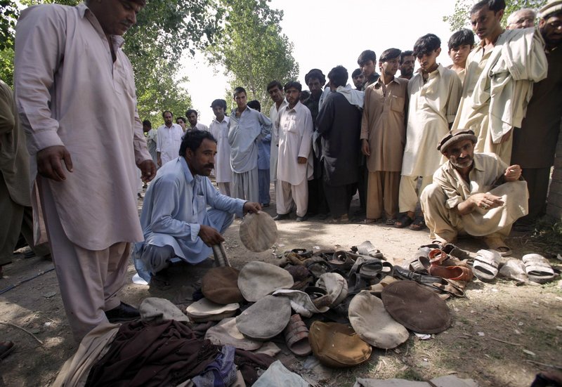 People look at the clothing and shoes of victims at the site of suicide bombing in Kacha Puka, Pakistan on Saturday.