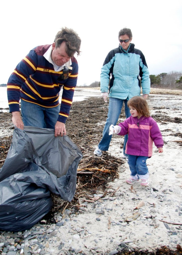 Derrick Daly, head gardener at the Inn by the Sea in Cape Elizabeth, holds a bag open for Kate Hetrick, 2. She and her mother, Eileen, were among volunteers taking part in the annual cleanup of Crescent Beach on Sunday. “It’s important to teach our kids to be a part of the community and to give back,” said Kate’s mom, of Cape Elizabeth.