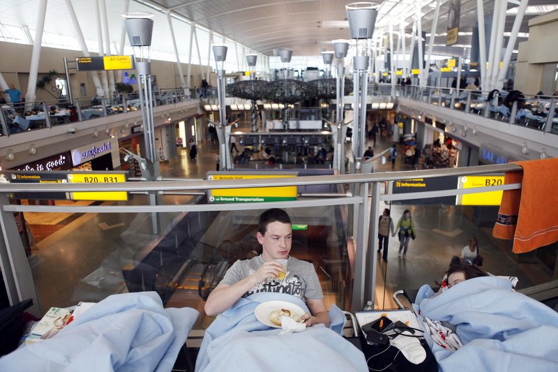 Huw Thomas, of England, eats breakfast in his cot at John F. Kennedy International Airport in New York on Monday. Thomas and his family were originally supposed to fly back to England from a vacation in New York on Friday.