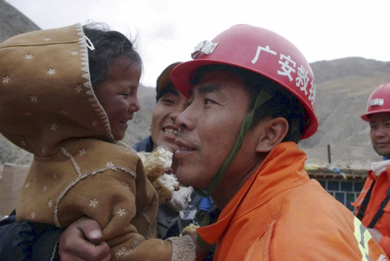 Four-year-old Cairen Baji is hugged by rescue workers Monday after they dug her and an elderly woman from a collapsed mud house near Jiegu, China. The rescue was hailed by state media as a miracle, with footage played repeatedly on television news.