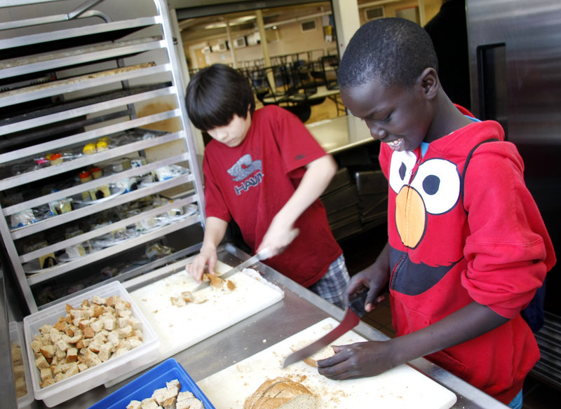 Lincoln Middle School seventh-graders David Mathew, right, and Jordan Sparks cube bread to be used for croutons in the kitchen at Preble Street Resource Center.