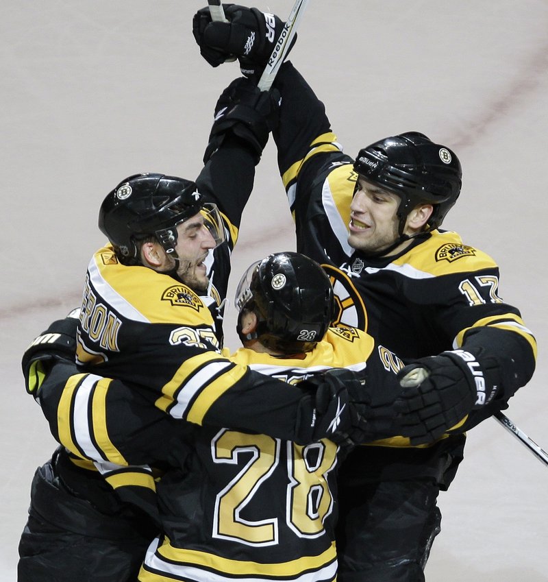 Patrice Bergeron, left, is congratulated by teammates Mark Recchi, 28, and Milan Lucic after scoring what would be the winning goal against the Buffalo Sabres on Monday night at the TD Garden in Boston.