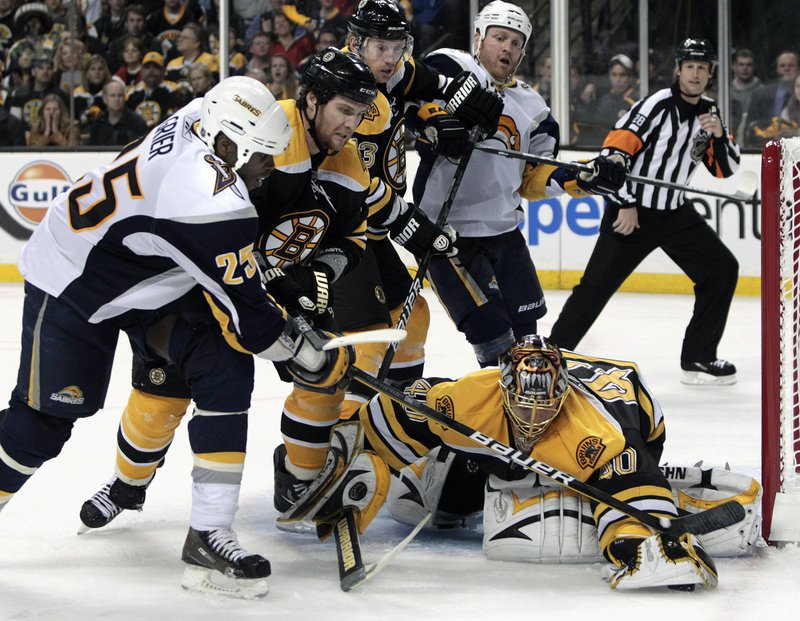 Bruins goalie Tuukka Rask covers the puck after an attempt by Buffalo Sabres right wing Mike Grier, left, as Bruins’ Dennis Wideman, middle, holds him off Monday night.