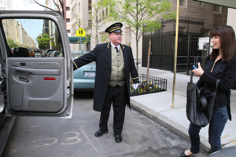 A concierge at a building on New York’s Park Avenue holds the door for a woman as she gets into a car Tuesday. New Yorkers are bracing for a possible strike by 30,000 doormen, porters and other building workers who keep residential high-rises running smoothly.