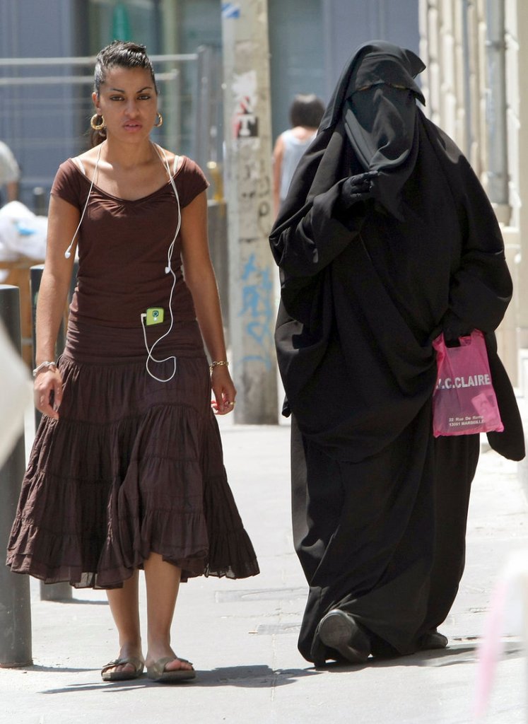 A conservative Muslim niqab, worn at right in Marseille, France, exposes only a woman’s eyes. Muslim veils in public may be banned later this year.