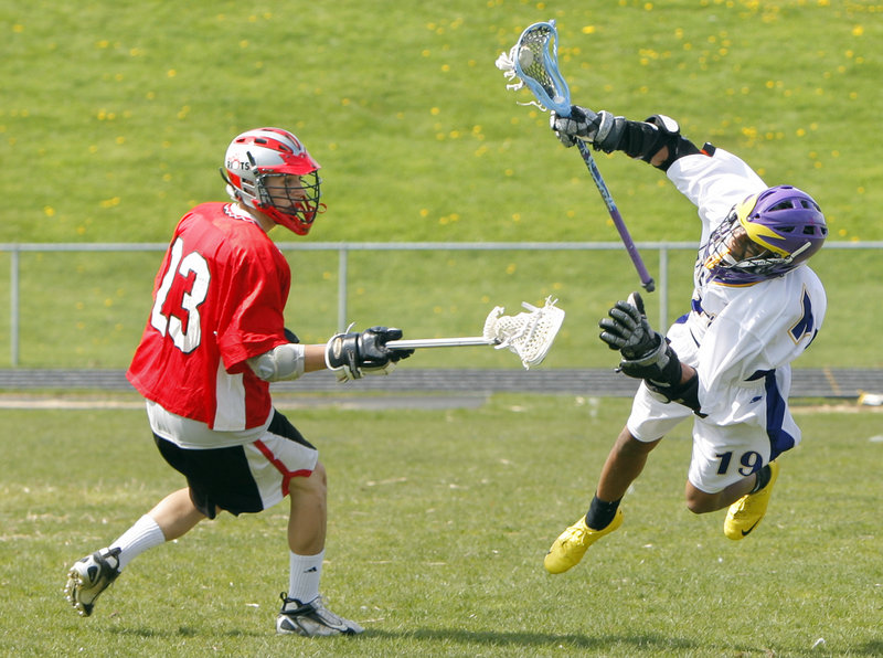 Garrett Naimie of Cheverus takes to the air Wednesday while advancing the ball against Chad Macleod of South Portland during South Portland's 8-3 victory in boys' lacrosse.