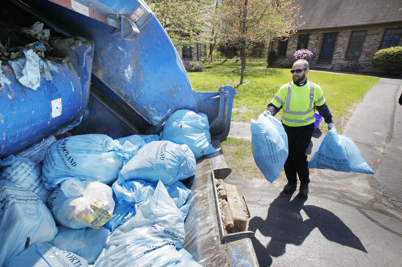 Jerry Mains throws a trash bag into the back of a garbage truck on Coachlight Lane in Portland Thursday. City Manager Joe Gray has suggested raising the fee for pay-per-bag trash bags.