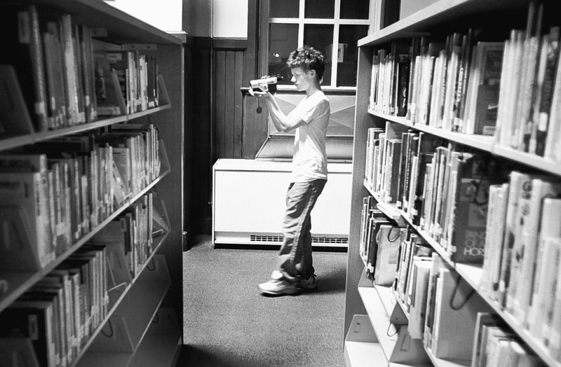 Student Dylan Sargent, 18, films Kara Marston, out of view, as she asks questions and hopes for a paranormal response in the Portland High library. The school has long been rumored to be haunted by restless spirits.