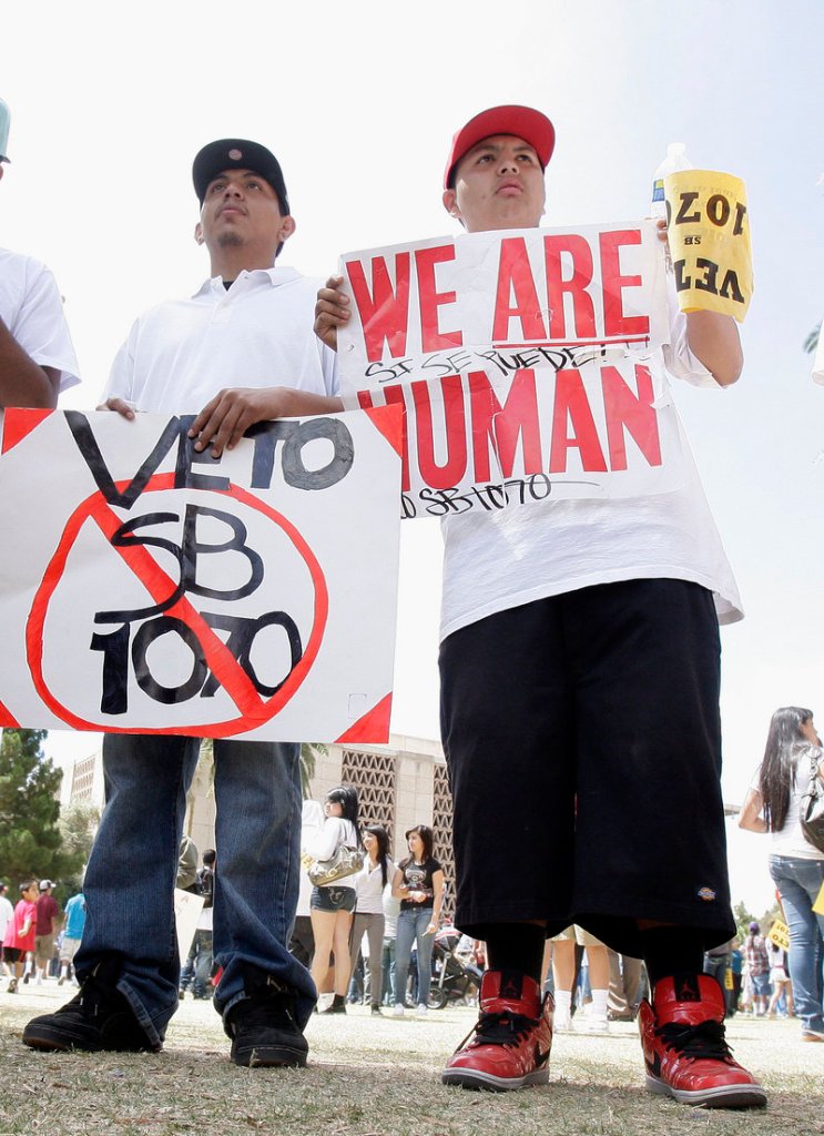 Edgar Rios, left, and Marcos Gonzalez rally against the Arizona immigration bill before it was signed into law Friday.