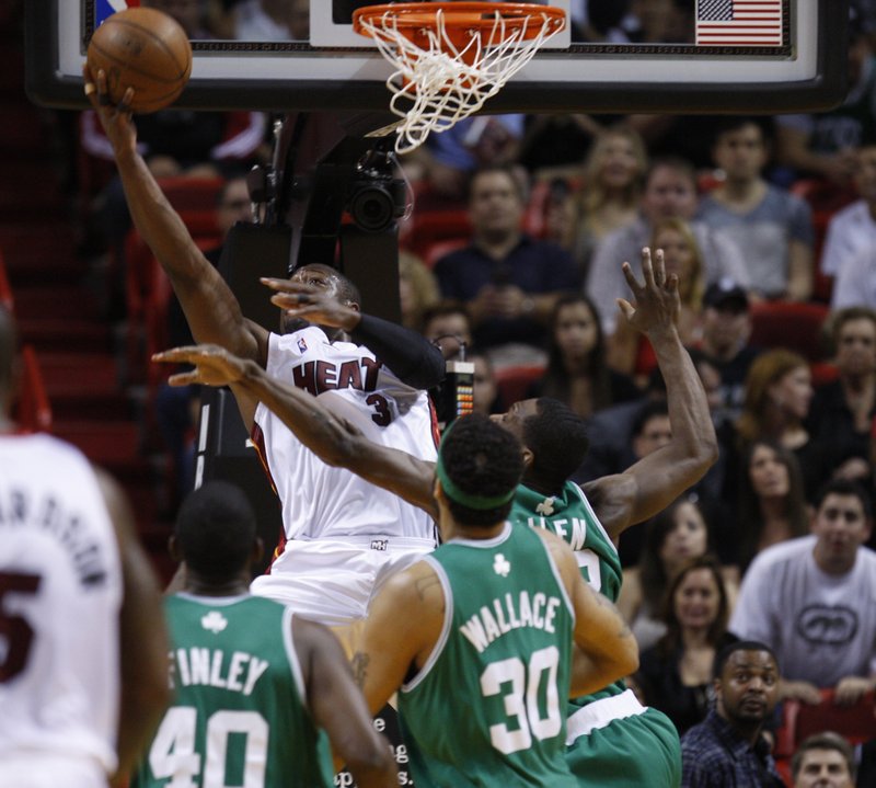 Dwyane Wade of the Miami Heat slips inside against Boston’s Michael Finley, left, Rasheed Wallace and Tony Allen for a reverse layup Sunday, two of his 46 points in Miami’s 101-92 playoff win.