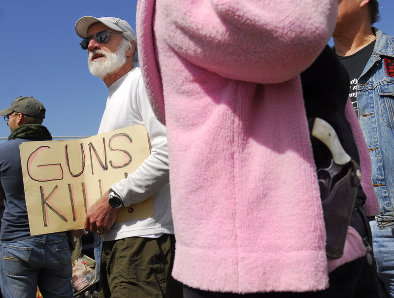 Michael Beaudoin of Portland carries a sign reading "Guns Kill" during an open-carry gathering at Back Cove in Portland on Sunday. To his disappointment, Beaudoin was soon asked by police to join other gun control advocates who were kept separated from the rally. "(Police) said, 'This is not a place for dialogue,'" he said.
