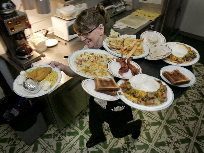 Server Joyce Smith carries plates of food to her customers at the Vail Steak House in Vail, Ariz. After nearly two years of stagnation, sales began to increase in March at many chain restaurants around the country, possibly indicating more confidence in the economy.
