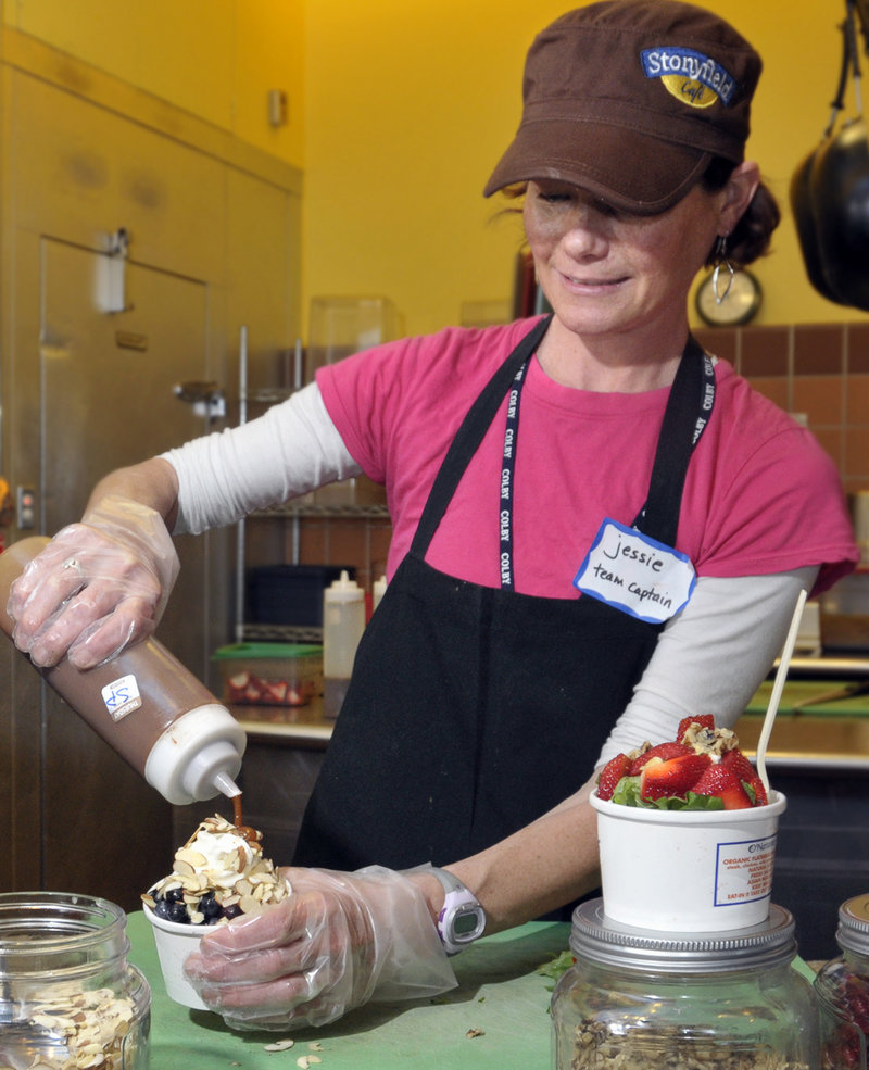 Stonyfield Cafe general manager Jessie Mullen puts together a couple of frozen-yogurt treats for customers at the Falmouth eatery. That’s spicy peanut sauce she’s drizzling on one of them.
