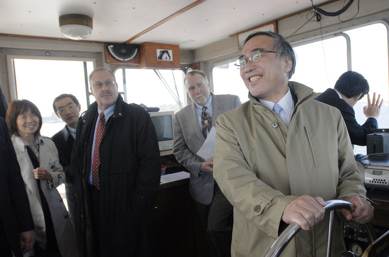 Takeshi Hamano, mayor of Shinagawa, Japan, steers the ferry Monday during a trip to Peaks Island. With him are dignitaries from Portland's sister city along with former Mayor David Brenerman, in dark coat, and Tom Morse, right, a relative of Edward Sylvester Morse, who is honored in Japan.