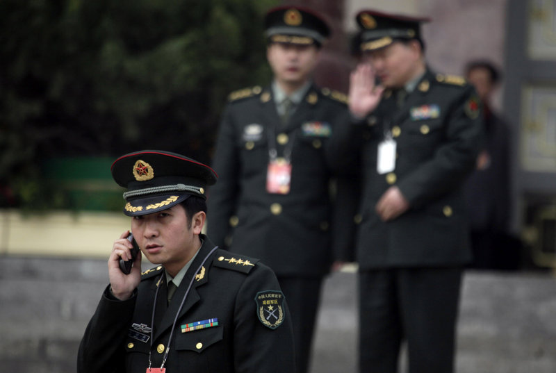A Chinese military officer uses his mobile phone outside the Great Hall of the People in Beijing. China is about to pass a law requiring telecom companies and Internet service providers to report discussions of “state secrets,” but critics say the law is aimed at stifling dissent by political activists.