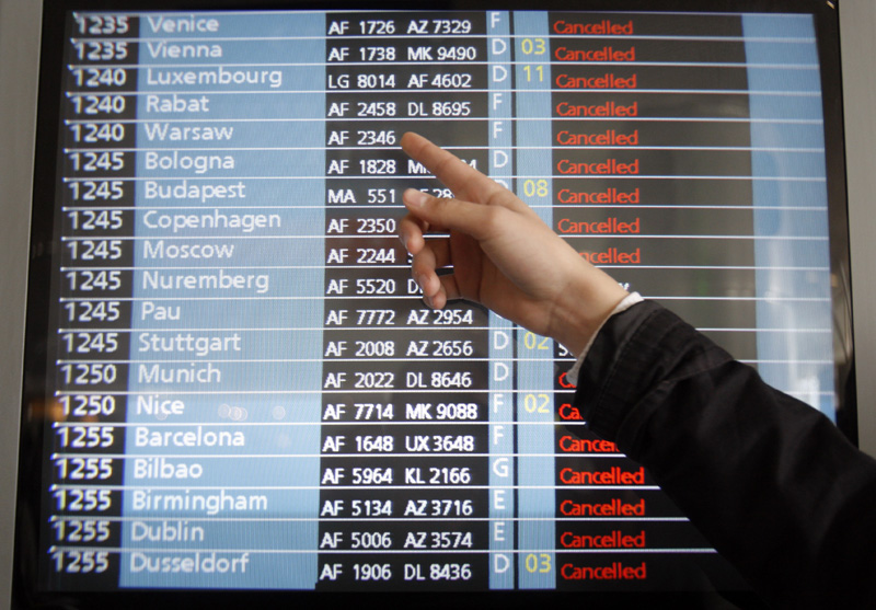 A passenger points to a flight information screen at Roissy Charles de Gaulle Airport outside Paris, as hundreds of commercial flights across northern Europe are canceled.