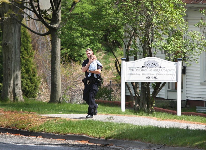 Eric Nevins, a Portland Police Department negotiator, carries a 5-month-old baby from an apartment during a police standoff Sunday on outer Forest Avenue.