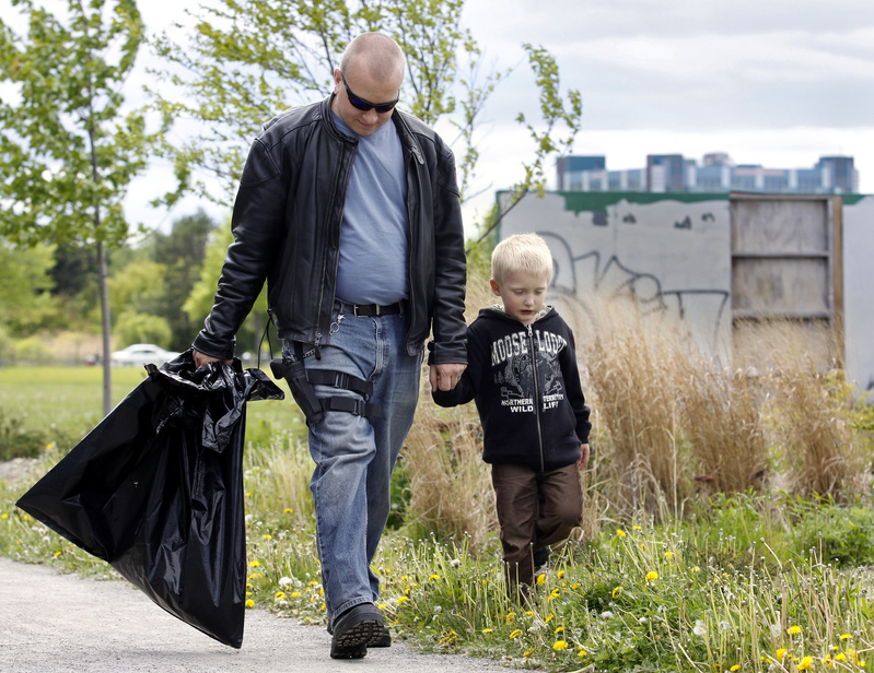 Josh Spicer of West Bath walks with his five year-old son Ryan during an open-carry trash pickup at Back Cove in Portland today.
