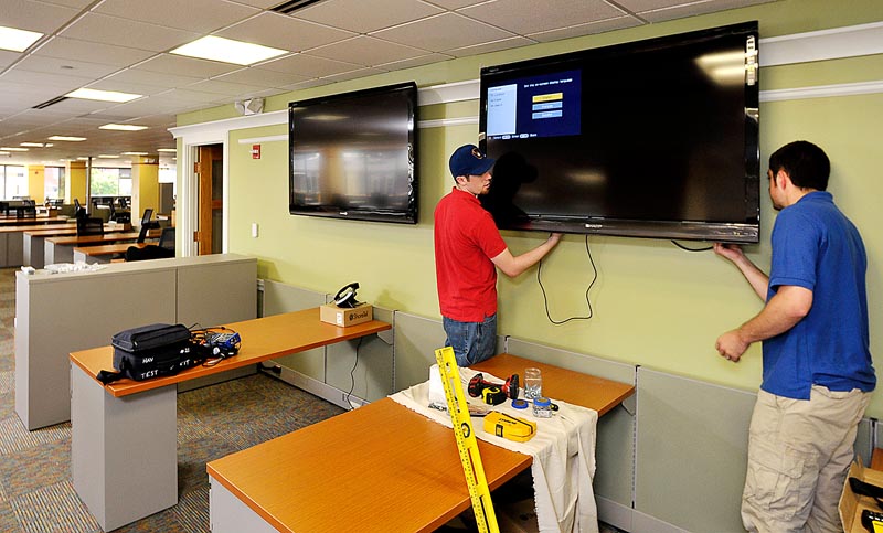 Nicholas Robertson and Alex Shupe, installation technicians for Headlight Audio Visual Inc., install a 60-inch Sharp HD flat screen TV, one of 19 flat screens installed throughout the MaineToday Media new headquarters at One City Center.