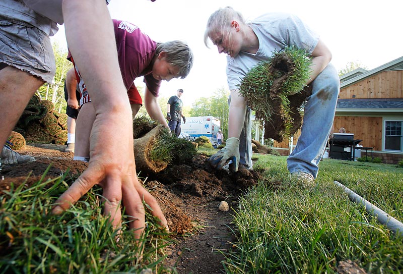 Kyle Sheriff, left, and Annette Thibodeau pull up a section of sod at the Lebanon Town Office on Monday. The sod, which recently had been laid down for the dedication of a monument to the town’s Civil War soldiers, was damaged by vehicles driven over it Sunday. Tuckahoe Turf Farms donated the new sod, and volunteers replaced it Monday.