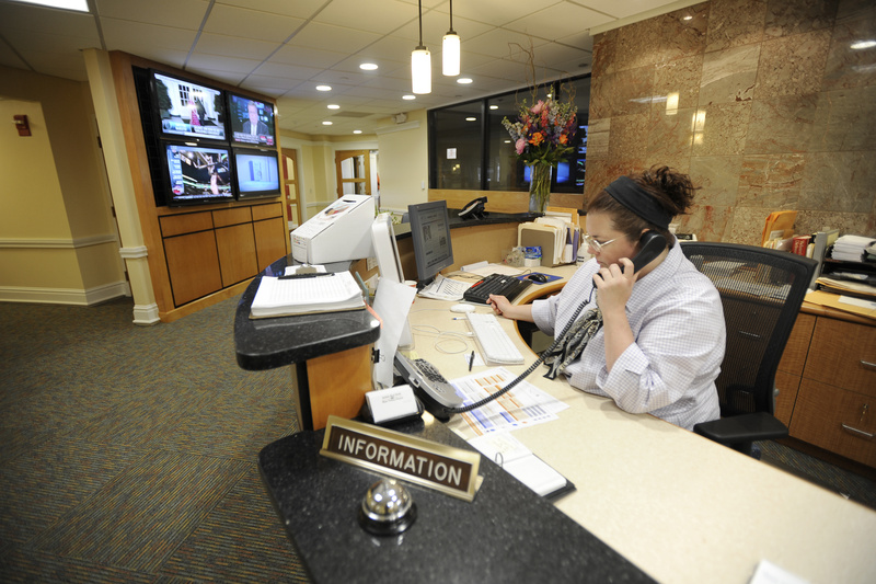 Ann Walsh answers the phone Tuesday in the Press Herald/Telegram reception area, which has four video monitors for viewing by visitors, including some that will display the media company’s websites.