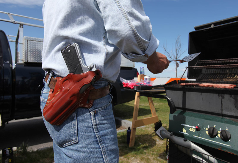 A gunowner wears a .45-caliber semi-automatic pistol as he barbecues at the first "open-carry" gun-rights rally on April 25 at Back Cove. Portland used to put limits on carrying guns openly in public, but the state Legislature later prohibited communities from regulating firearms.