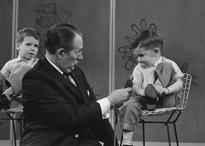 In this April 5, 1962, file photo, TV personality Art Linkletter talks with 4-year-old Ronnie Glahn, who shows Linkletter his idea of how bad guys look, on Art's TV show "People Are Funny." Childhood,Communication,Fame,Holding,Microphone,Sitting